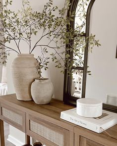 a dog laying on the floor in front of a table with vases and books