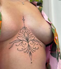 a woman with a tattoo on her stomach is showing it's large breast area