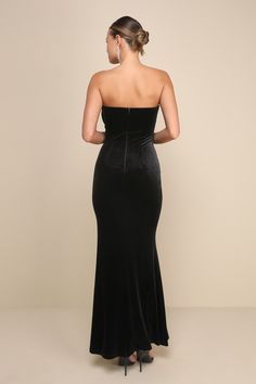 a woman wearing a black velvet gown with one shoulder and an open back, looking down at