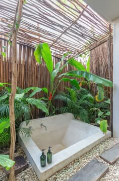 an outdoor bathtub surrounded by plants and rocks