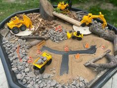 there are construction vehicles in the sand on this play set that is made out of rocks and wood