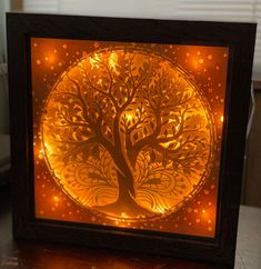 an illuminated tree in a wooden frame on a table