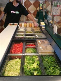 a man standing in front of a counter filled with lots of salads and condiments