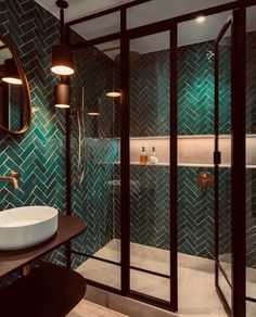 a bathroom with green tiles and gold fixtures on the wall, along with a round sink