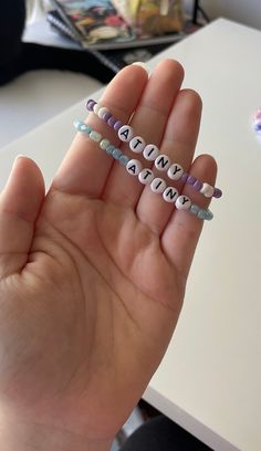 a person holding some type of beaded bracelets in their hand with the word love spelled on it