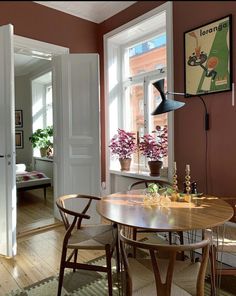 a dining room table and chairs in front of an open door with potted plants