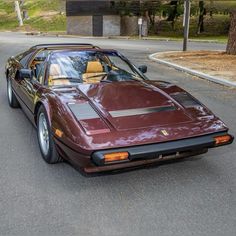 a maroon sports car is parked on the side of the road