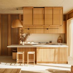 a kitchen with wooden cabinets and stools in front of an island countertop that has two plants on it