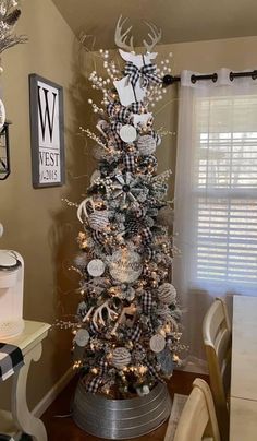 a christmas tree decorated with silver and white ornaments in a living room area next to a window