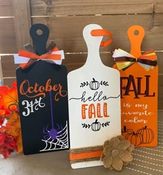 three handmade halloween gift tags on a table with pumpkins and fall decorations in the background