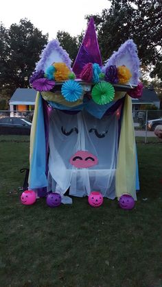 an inflatable costume is sitting on the grass with its eyes closed and colorful hair