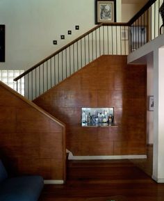 a living room filled with furniture and a stair case next to a wall mounted clock