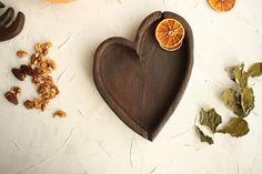 a heart shaped cutting board with oranges and walnuts on the table next to it