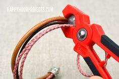 a pair of red pliers are being used to make bracelets with leather cords