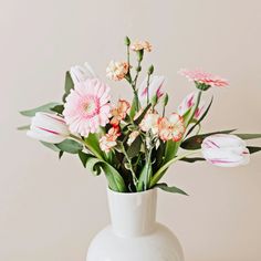 a white vase filled with pink and white flowers