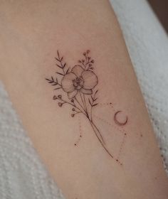 a small flower and crescent tattoo on the arm