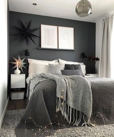 a bedroom with grey walls and white bedding, two framed pictures on the wall