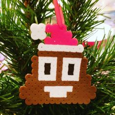 a christmas ornament hanging from a tree with a pink hat on it's head