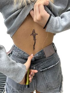 a woman with a small tattoo on her lower back is holding a pencil in her left hand