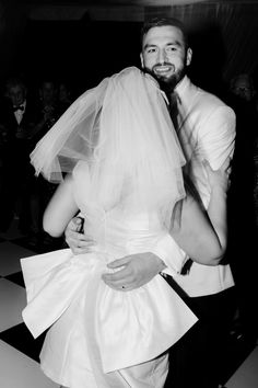 a bride and groom hugging each other in the middle of a dance floor with people looking on