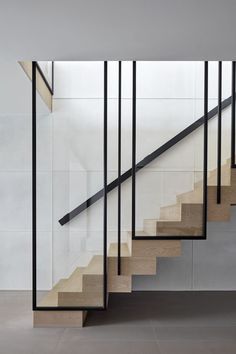 a set of stairs with black railings and wooden handrails in front of a white wall