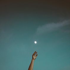 a person reaching up into the sky to catch a frisbee