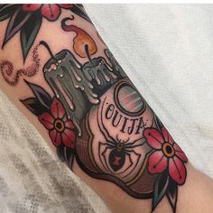 a tattoo on the arm of a woman with flowers and an old fashioned camera in it