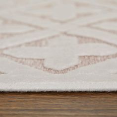 a close up view of a white rug on a wooden floor with an intricate design