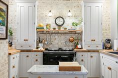 a kitchen with white cabinets and marble counter tops, along with a clock on the wall