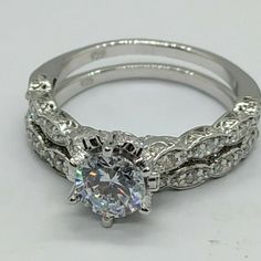 a white gold ring with an oval diamond center surrounded by intricate filigrees