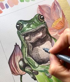 a drawing of a frog with flowers on it's back and one hand holding a marker