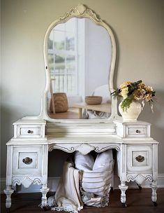 an antique white dressing table with mirror and vase