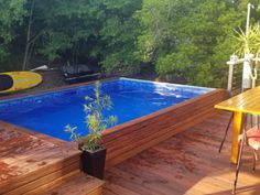 an above ground swimming pool surrounded by wooden decking and trees in the back yard