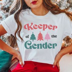 "🤶Get ready for the holiday season with the 'Christmas Keeper of the Gender' T-Shirt! Perfect for XMas gender reveal parties, this festive tee is a must-have for team boy or girl supporters. Ideal for winter holiday baby showers, it's a fun way to involve everyone, especially the proud auntie. Don't wait, grab this joyful top and become the ultimate gender keeper this Christmas! Click ADD TO CART now! 👕 PRODUCT INFO The Bella + Canvas shirts are super soft and comfy! They fit true to size so choose your usual size for the best fit! If you would like to wear this shirt for your entire pregnancy, I recommend going up a size! The solid colored shirts are 100% cotton. And the heather colors and Solid Black Blend are 52% cotton, 48% polyester. ✏️ DESIGN Designs are printed onto the shirt usin Fun Short Sleeve Winter Tops, Trendy Cotton Christmas Tops, Gender Reveal Keeper Shirts, Playful Cotton T-shirt For Gender Reveal, Cute Graphic Print T-shirt For Gender Reveal, Gender Keeper, Fun Custom Print T-shirt For Gender Reveal, Keeper Of The Gender Shirt, Keeper Of The Gender