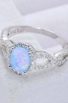 a white opal and diamond ring sitting on top of a table