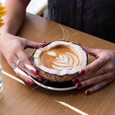 two hands holding a cup of coffee on top of a plate