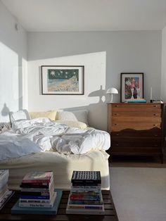 a bedroom with a bed, dresser and books on the table in front of it