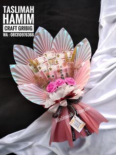 a bouquet of flowers is wrapped in pink and white paper with the words taslimah hamm on it