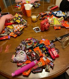 several people sitting at a table with candy and candies on the table, one holding a cell phone