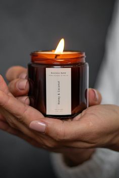 a person holding a candle in their hands with a label on it that says,