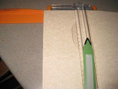 a green pencil sitting on top of a piece of paper next to an orange ruler