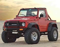 a red truck parked on top of a sandy beach