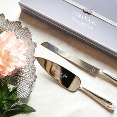 two silver serving utensils sitting on top of a table next to a flower