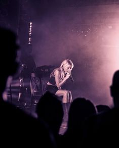 a woman sitting on top of a chair in front of a crowd at a concert