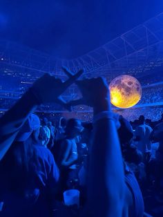 a crowd of people at a concert with their hands up in front of the audience