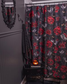 a black and red shower curtain with flowers on it next to a night stand in front of a mirror