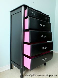 a black dresser with pink drawers in a room