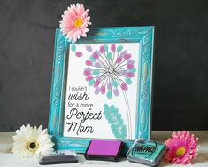 some pink flowers are sitting in front of a picture frame and three small magnets