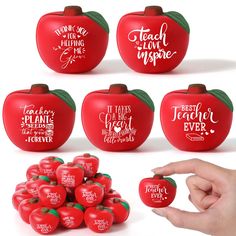 there are many red apples with words on them and one hand is holding the apple