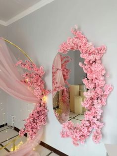 a mirror with pink flowers hanging on it's side next to a wall in a room